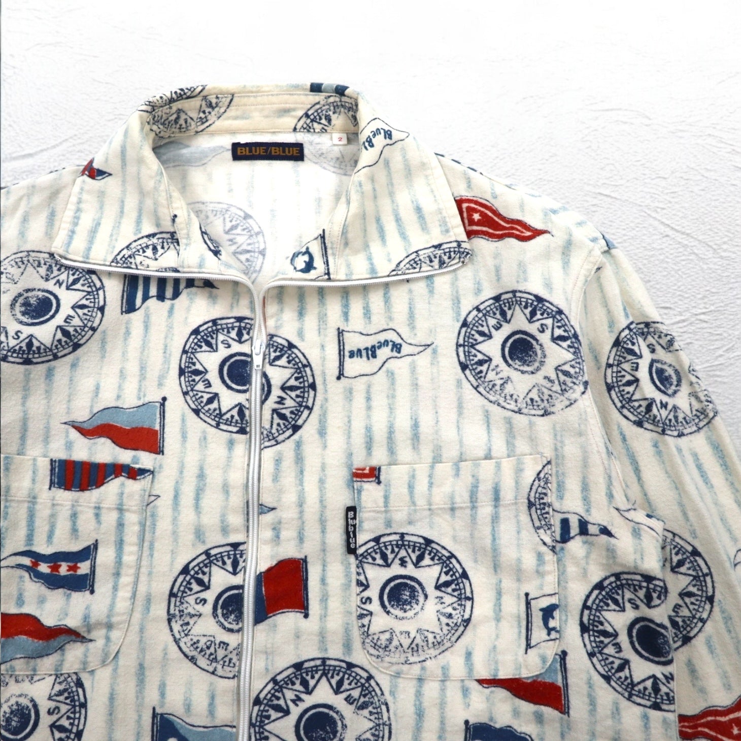 BLUE BLUE Giacca con cerniera a collo alto, taglia M, bianca, fantasia all-over, motivo a bandiere nautiche, made in Japan